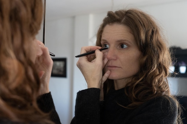 Close-up shot van een blanke vrouw die make-up aanbrengt voor een spiegel