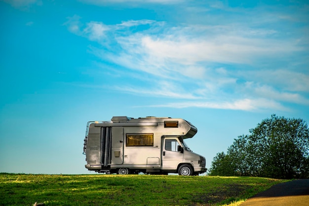 Close-up shot van een camper geparkeerd in het groene veld onder de blauwe lucht