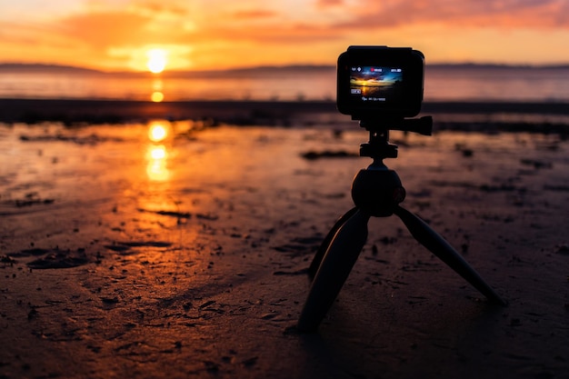 Close-up shot van een Go Pro-camera op het zand van het strand die de prachtige zonsondergang opneemt