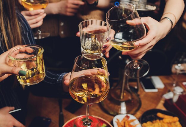 Foto close-up shot van een groep mensen rammelende glazen met wijn of champagne voor bokeh achtergrond oudere mensen handen