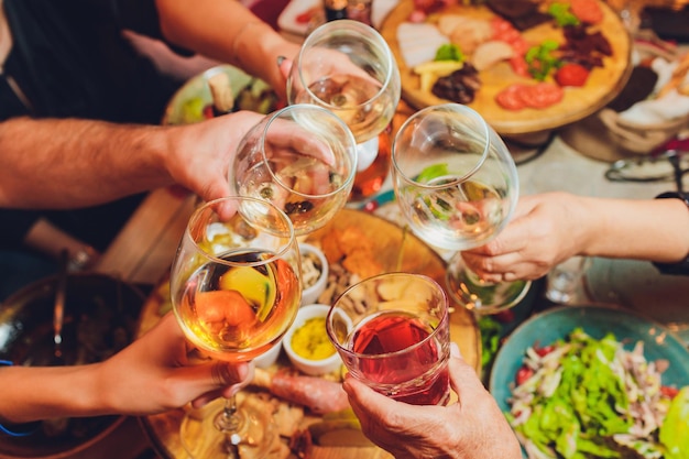 Foto close-up shot van een groep mensen rammelende glazen met wijn of champagne voor bokeh achtergrond oudere mensen handen