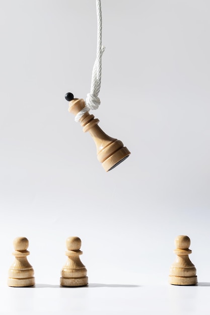 Close-up shot van een houten schaakkoningin hangend aan een wit touw met pionnen die eronder staan Concept van publieke afkeuring onder ogen zien en belast worden met verantwoordelijkheid