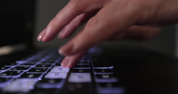 Close-up shot van een jonge vrouw die druk bezig is met het werken op een laptop of computertoetsenbord om 's nachts e-mails te verzenden en te surfen op een webbrowser