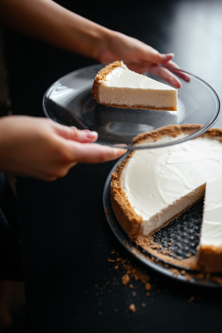 Close-up shot van een stuk cheesecake op een bord naast een hele cheesecake
