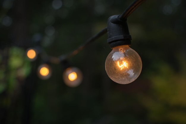 Foto close-up shot van een verlichte gloeilamp die aan een touwtje hangt