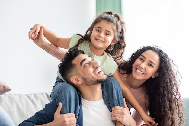 Close-up shot van gelukkige Arabische gezin van drie met dochtertje plezier samen thuis, portret van vrolijke Midden-Oosterse ouders spelen met hun kind In de woonkamer, genieten van Weekend