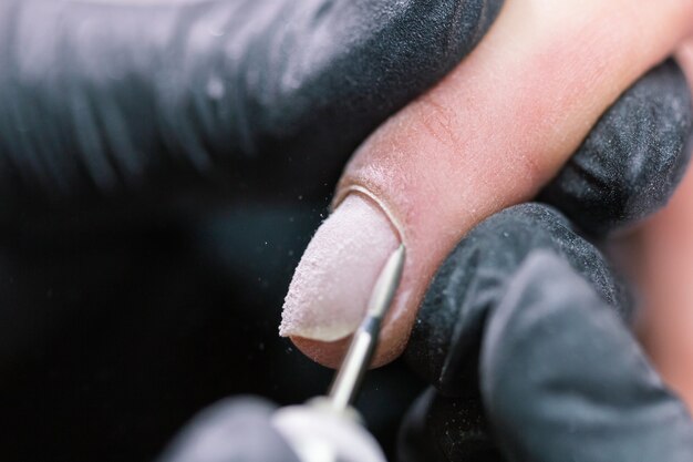 Close-up shot van hardware manicure in een schoonheidssalon. Manicure past elektrische nagelvijl toe