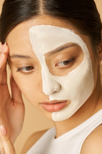 Close-up shot van jonge vrouw met gezichtsmasker aangebracht op de helft van haar gezicht