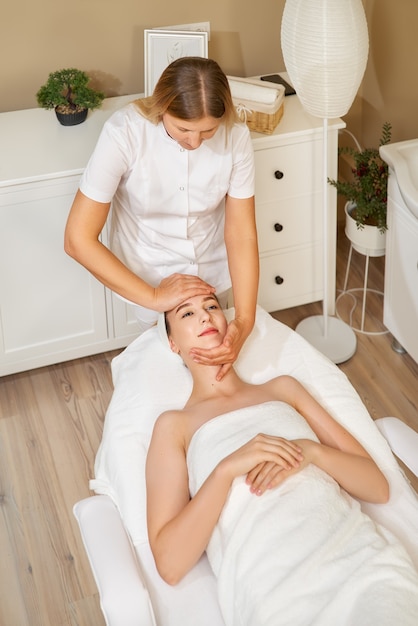 Close-up shot van jonge vrouwelijke masseur massage op het gezicht maken voor jonge mooie vrouwelijke cliënt in de spa salon.