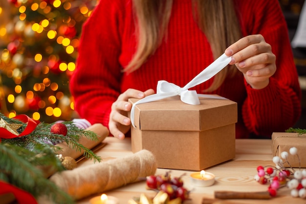 Close-up shot van meisje dat cadeautjes voorbereidt voor naaste mensen die de strik op de doos controleren en deze aanpassen om er mooi uit te zien Bereid kerstcadeaus voor