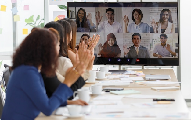 Close-up shot van multiculturele zakenman zakenvrouw collega's op teleconferentie op beeldscherm begroeting zeggen hallo tegen vrouwelijke officier staf groep in formele pak zitten zwaaiende handen samen.