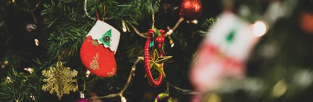 Close-up shot van rode en witte nep sneeuw versierde sok opknoping versieren op groene dennenboom kerstboom tak voor onscherpe achtergrond in Xmas Eve traditionele festival viering nacht evenement.