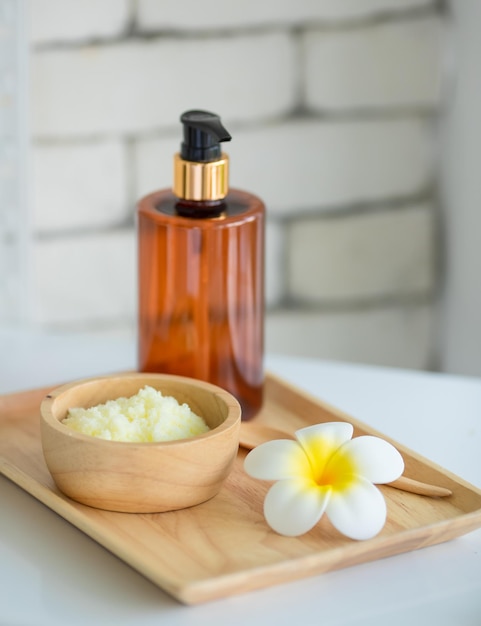 Close-up shot van Thaise massage spullen kruiden handdoek kompres bal, kokosolie, parfum, cosmetica en plumeria bloem in houten dienblad plaatsen op massage bed in spa therapie voorbereiding voor klant.