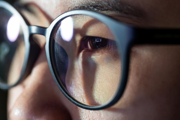 Close-up shot van vrouw ogen in glazen als gevolg van een werkende computer blauw scherm