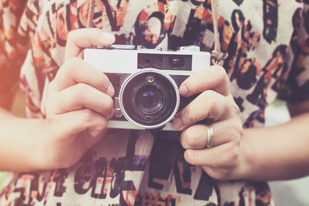 Close-up shot van vrouwelijke hand met retro camera. jonge hipster meisje fotograaf met filmcamera - vintage filter kleur effect stijl