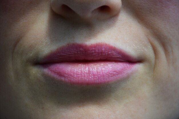 Close-up shot van vrouwelijke lippen en een deel van het gezicht beschilderd met roze lippenstift of lipgloss