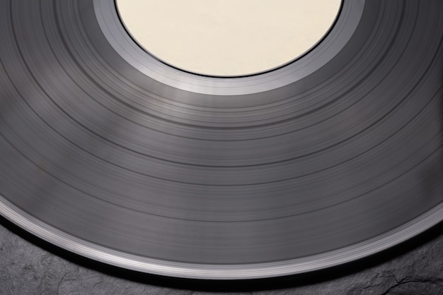 Close-up shot of vinyl record on black surface. Side view