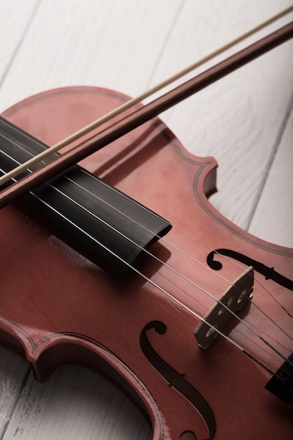 Orchestra di violino del colpo del primo piano strumentale con il tono d'annata elaborato sopra profondità di campo bassa del fuoco selezionato del fondo di legno bianco