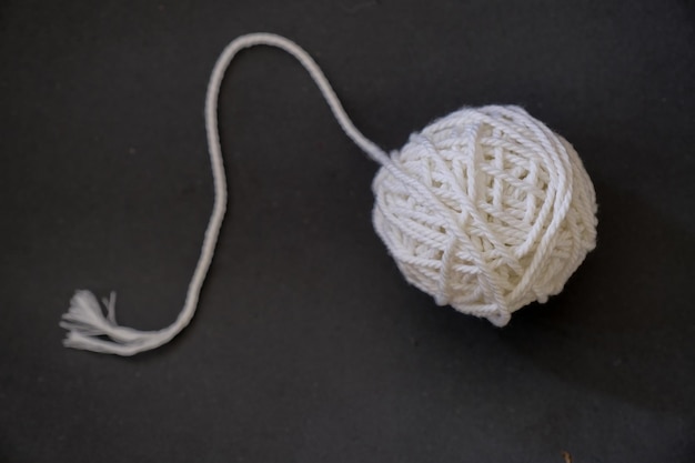 Close up shot of white ball of thread on black cloth
