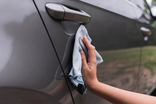 Colpo del primo piano con una mano che pulisce l'automobile