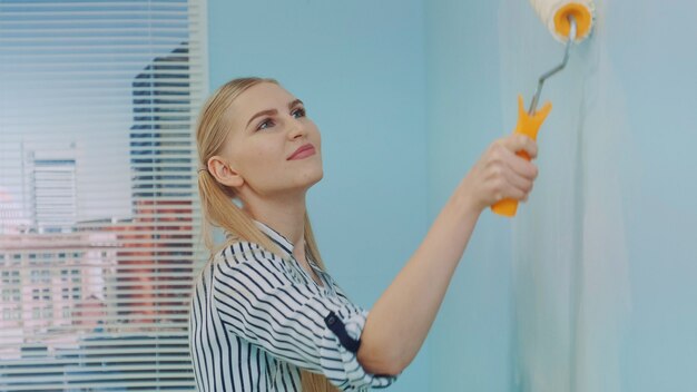 Close-up shot of woman builder painting wall.