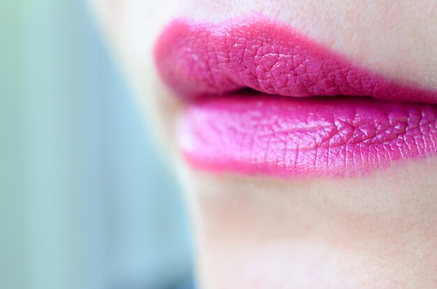 Close up shot of woman lips with glossy fuchsia lipstick