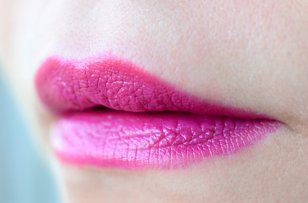 Close up shot of woman lips with glossy fuchsia lipstick