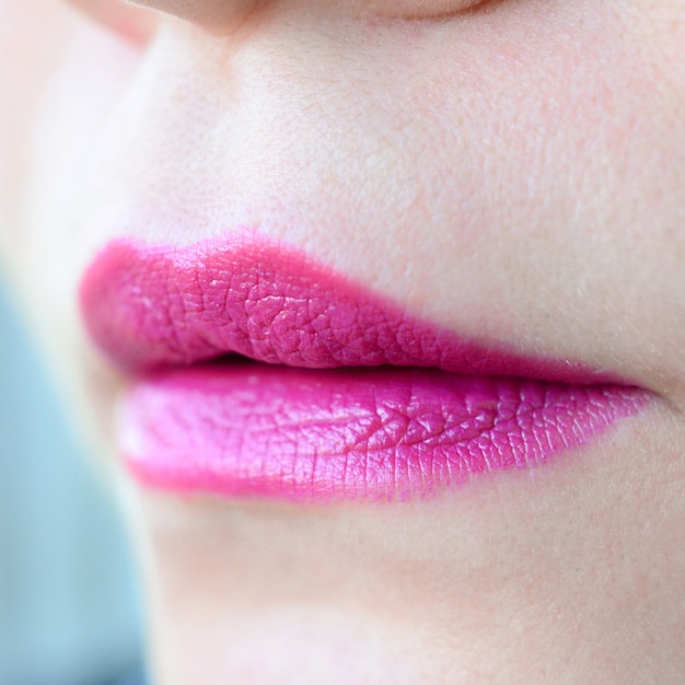 Close up shot of woman lips with glossy fuchsia lipstick