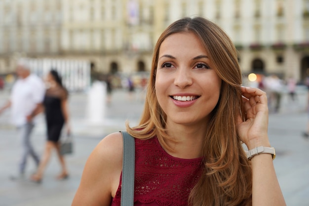 Close up shot of young beautiful surprised woman looks away against city blurred background