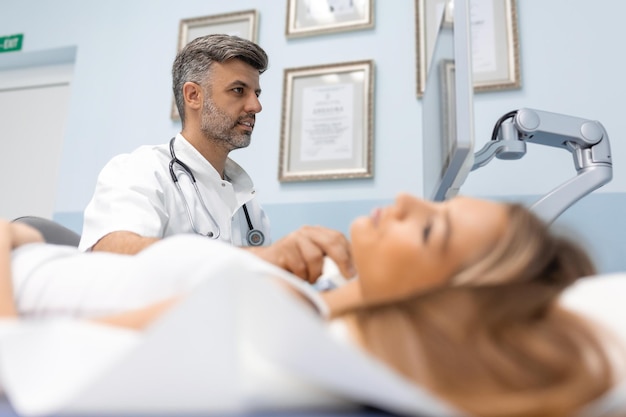 Close up shot of young woman getting her neck examined by doctor using ultrasound scanner at modern clinic