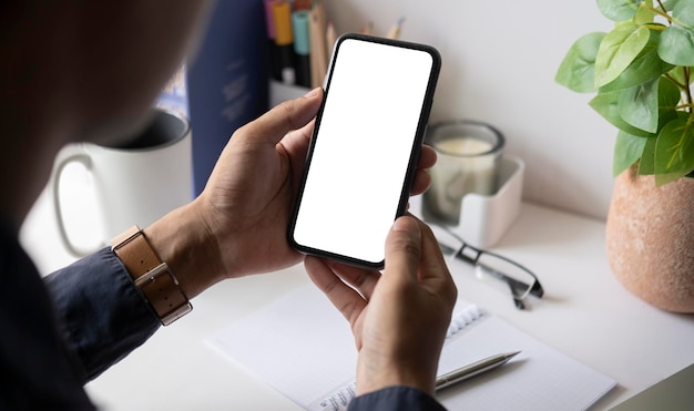 Close up over shoulder businessman using mobile phone at office desk