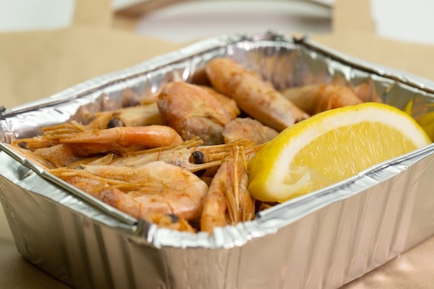 Close-up of shrimp in foil box for delivery and paper bag