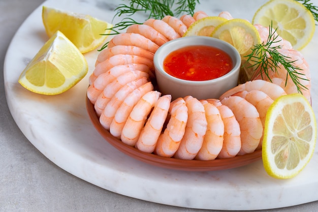 Close-up on shrimp ring with sweet chili sauce on marble serving board