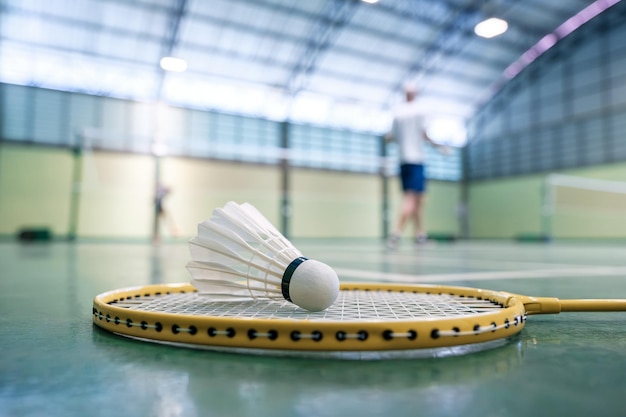 Close-up shuttle op badmintonracket op rechtbanken met concurrerende spelers