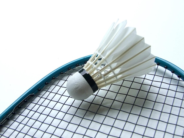 Close-up of shuttlecock and badminton racket over white background