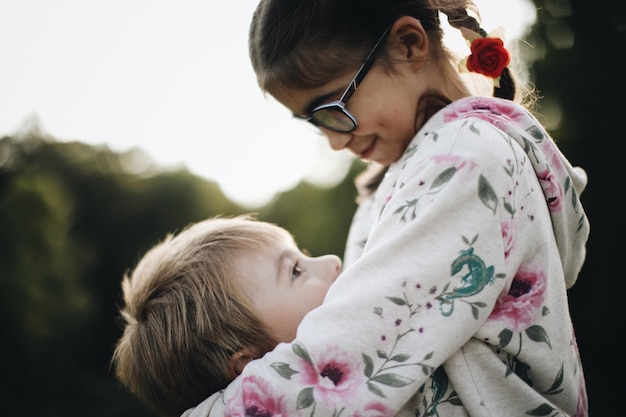 close-up of siblings embracing against sky