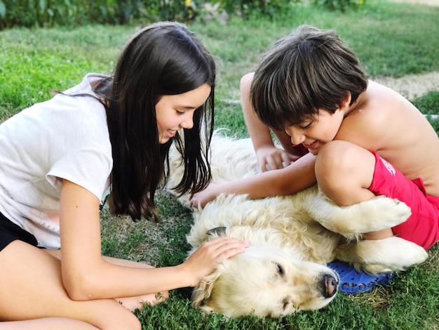 close-up of siblings playing with dog