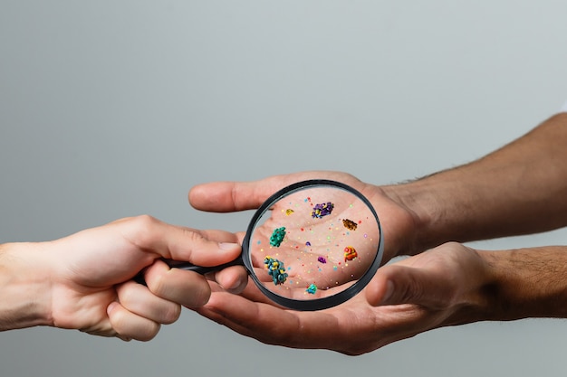 Close up on a sick man hand through magnifying glass\
transmitting virus by skin contact 3d rendering