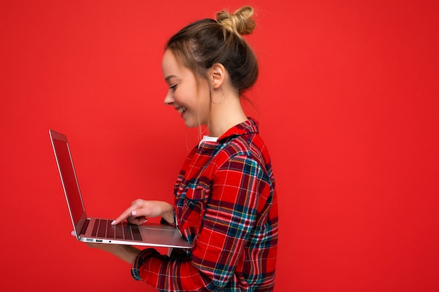 Close-up side profile photo of smiling young woman holding netbook
