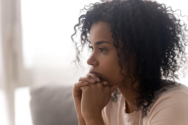 Close up side profile view of pensive young african American woman thinking of relationships problems thoughtful black biracial female feel despair lost in thoughts consider life trouble or drama