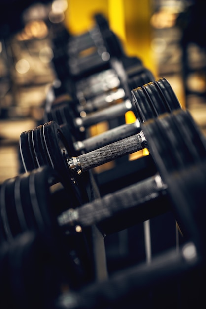 Close up side view of black dumbbells in a row in the gym.