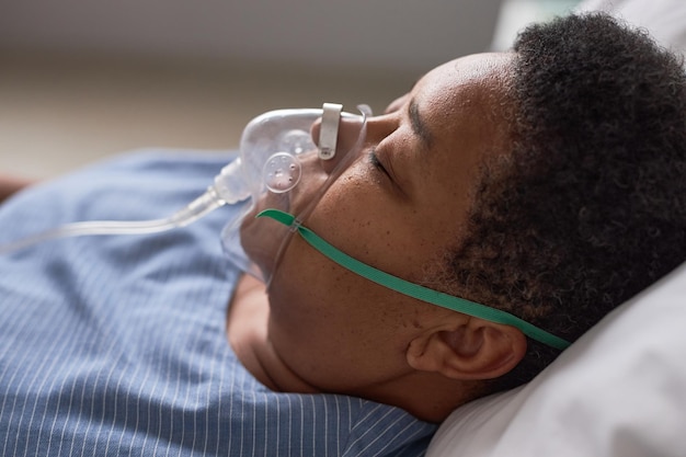 Close up side view of black senior woman with oxygen support mask in hospital