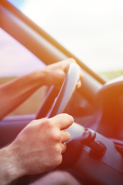 Close up side view shot of male hands on steering wheel while journey