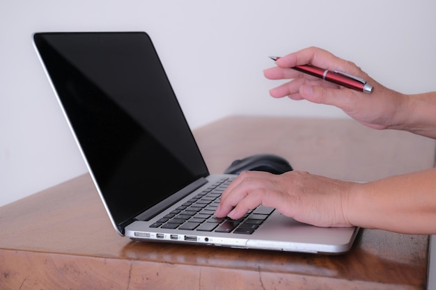Крупным планом Вид сбоку Женская рука на клавиатуре ноутбука, другая рука держит ручку