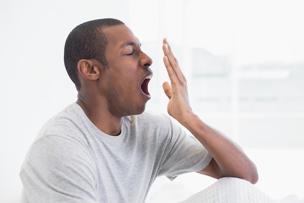 Close up side view of a young Afro man yawning