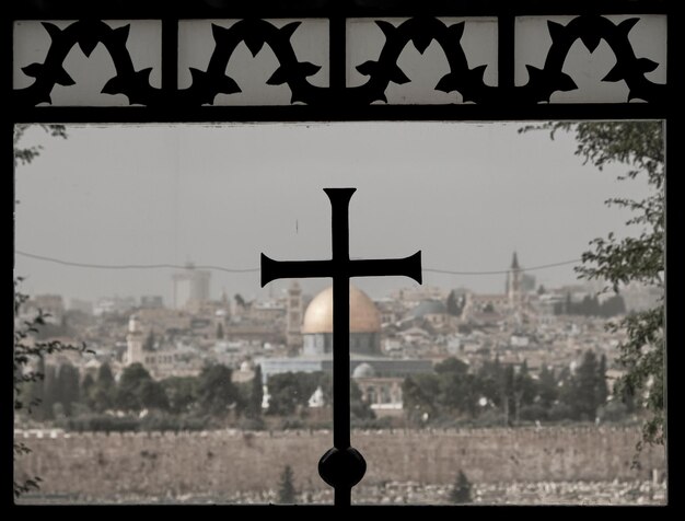 Close-up of silhouette cross on city against sky