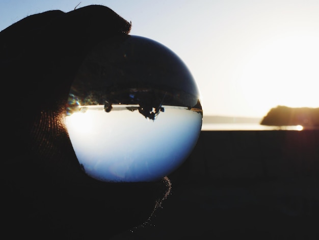 Foto close-up di una sfera di cristallo a silhouette contro il cielo durante il tramonto