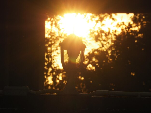 Close-up of silhouette person against illuminated sun during sunset