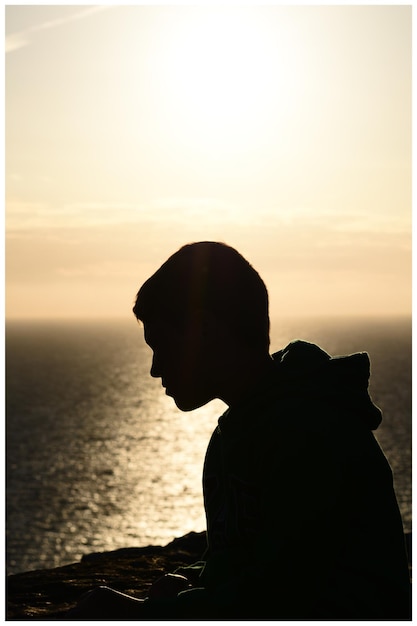 Photo close-up of silhouette of person by sea against sky