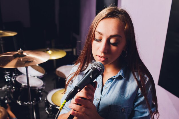 Close up of a singer recording a track in a studio.